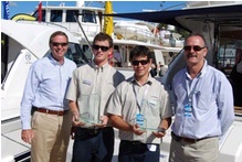 Director of Operations John Anderson (left) and General Manager New Product Development Phil Candler flank two Riviera apprentices holding Boat Of The Year Trophies at the Sanctuary Cove Boat Show. 