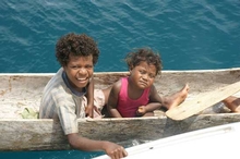 Children paddle out to visit Reynolds during his stay in Papua New Guinea
